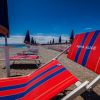Sdraio colorate e ombrelloni chiusi su una spiaggia di ghiaia.