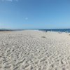 Spiaggia sabbiosa con mare azzurro e cielo sereno.