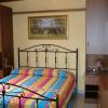 Camera con letto matrimoniale, coperta colorata, armadi di legno e quadro di paesaggio appeso.