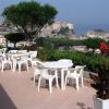 Terrazza con tavoli bianchi e vista panoramica su una città costiera.