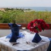 Tavolo elegante con vista mare e fiori rossi.