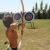 Un bambino mira a un bersaglio con un arco in un campo di tiro con l'arco.
