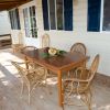 Veranda con tavolo in legno e sedie in vimini.