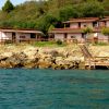 Case fronte mare con balconi su scogliera verde.