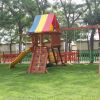 Parco giochi con scivolo e altalene in un prato.