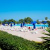 Piscina con lettini bianchi e ombrelloni blu.