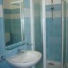 Bagno con piastrelle azzurre, lavabo e cabina doccia.