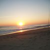 Un tramonto su una spiaggia sabbiosa con canna da pesca piantata nella sabbia.